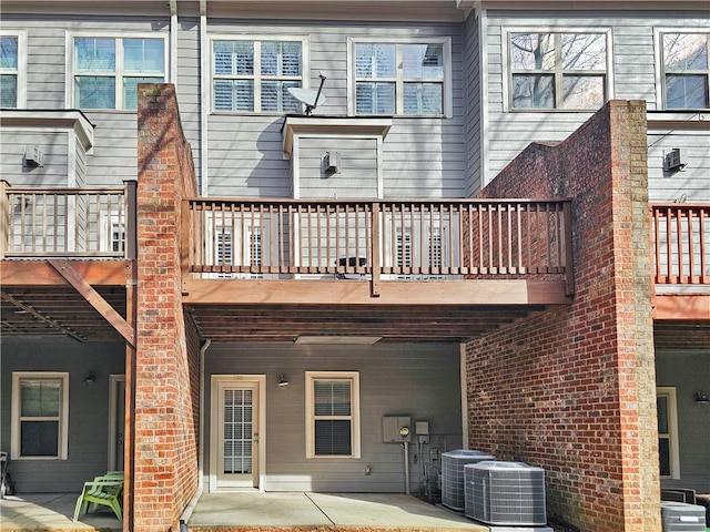 rear view of house featuring central AC, brick siding, and a patio area