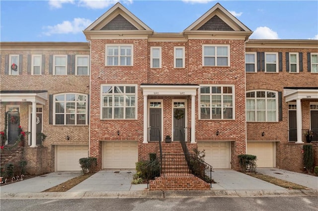 townhome / multi-family property with driveway, a garage, and brick siding