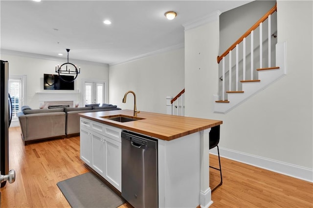 kitchen featuring wooden counters, light wood-style flooring, stainless steel dishwasher, white cabinets, and a sink