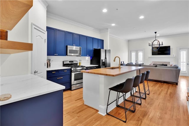 kitchen featuring a breakfast bar area, appliances with stainless steel finishes, french doors, blue cabinetry, and a sink