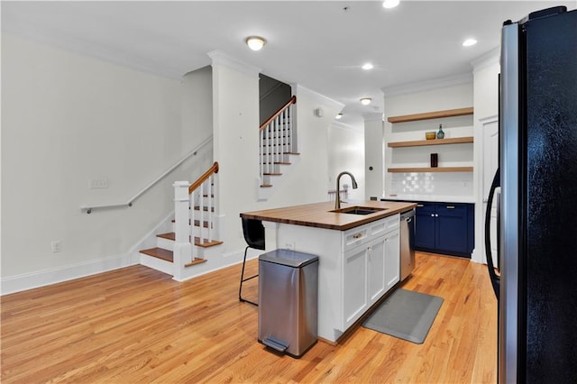 kitchen featuring open shelves, light wood-style flooring, freestanding refrigerator, a sink, and butcher block countertops