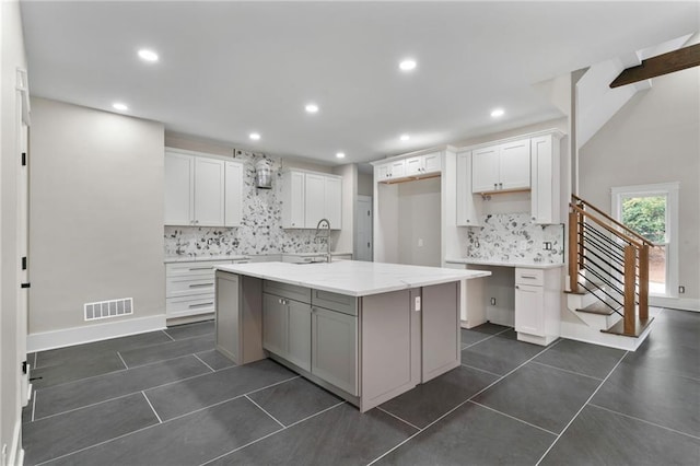1066 Fairway Valley Dr, Woodstock, GA 30189 - kitchen with backsplash, dark tile patterned flooring, recessed lighting, an island with sink, and white cabinets