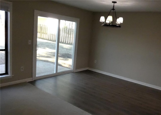 spare room with dark hardwood / wood-style floors and a notable chandelier