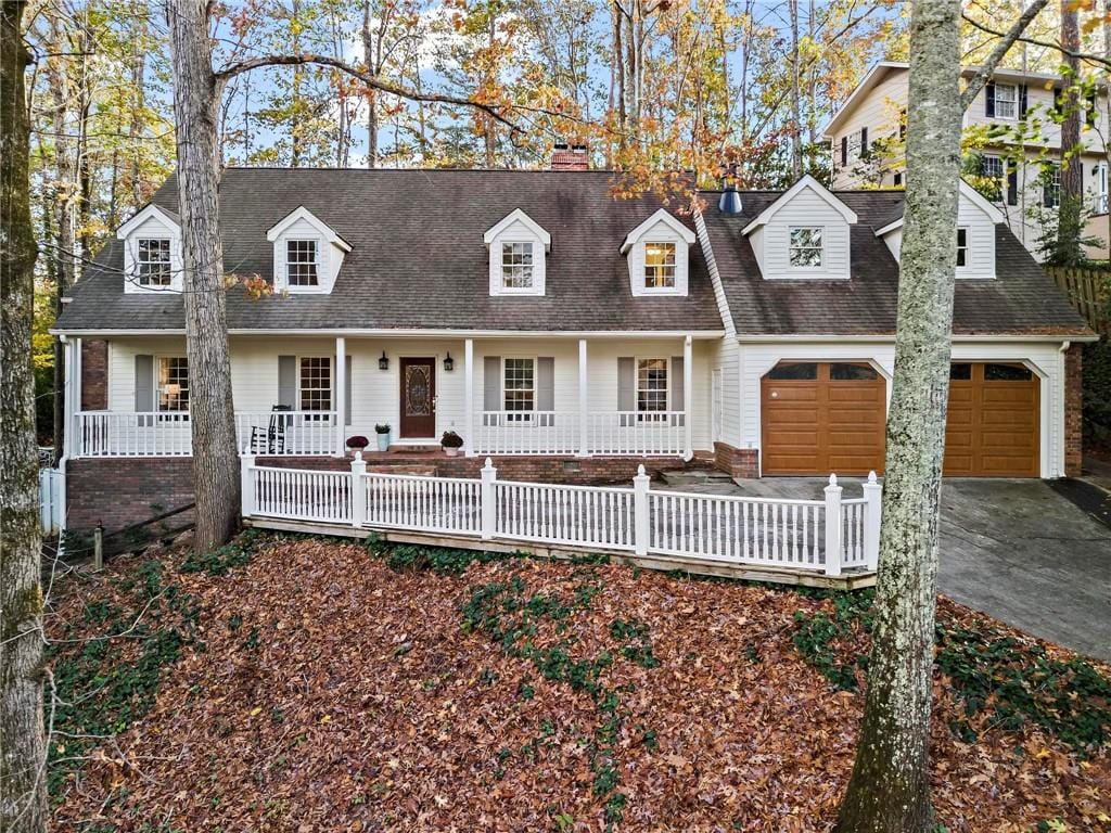 cape cod house with a garage and covered porch