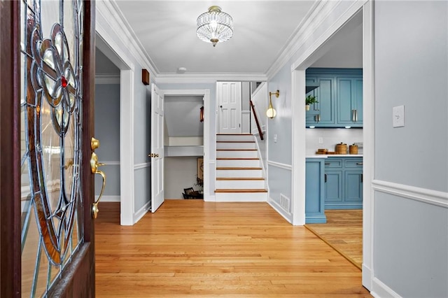 foyer entrance featuring crown molding and light wood-type flooring