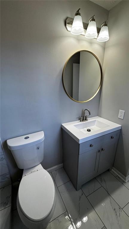 bathroom featuring marble finish floor, vanity, toilet, and baseboards