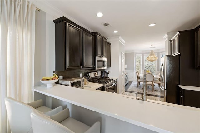 kitchen featuring visible vents, light countertops, appliances with stainless steel finishes, crown molding, and a chandelier