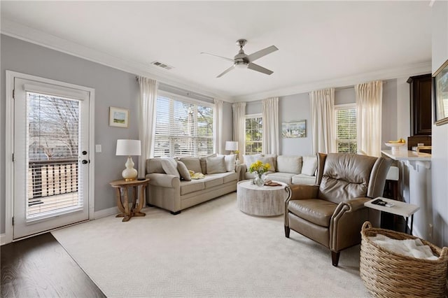 living room featuring visible vents, baseboards, ceiling fan, and crown molding