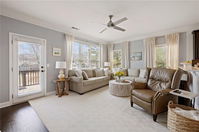 living room with wood finished floors, baseboards, visible vents, ceiling fan, and crown molding