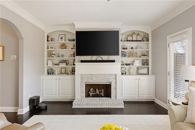 living area featuring built in features, baseboards, arched walkways, and dark wood finished floors