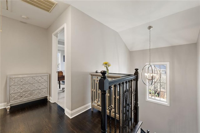 hall featuring visible vents, an upstairs landing, a notable chandelier, wood finished floors, and vaulted ceiling