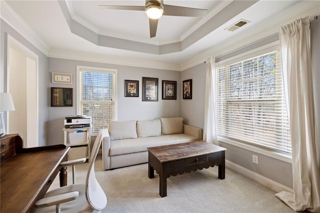 living area with visible vents, ceiling fan, a tray ceiling, carpet floors, and ornamental molding