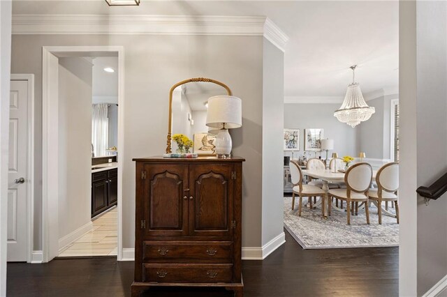 corridor with baseboards, an inviting chandelier, wood finished floors, and ornamental molding