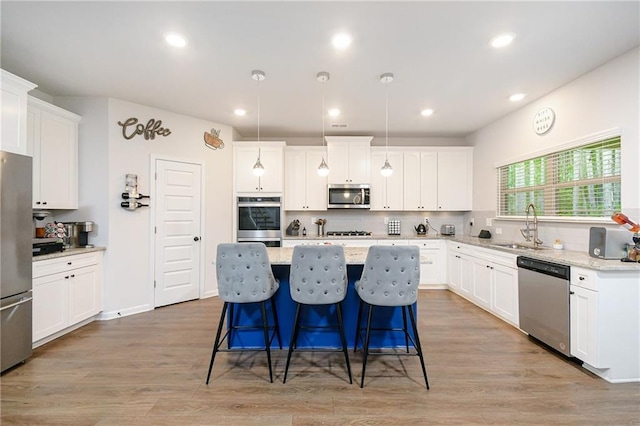 kitchen featuring sink, a center island, stainless steel appliances, and light hardwood / wood-style floors