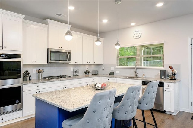 kitchen with a breakfast bar, a center island, sink, white cabinetry, and stainless steel appliances