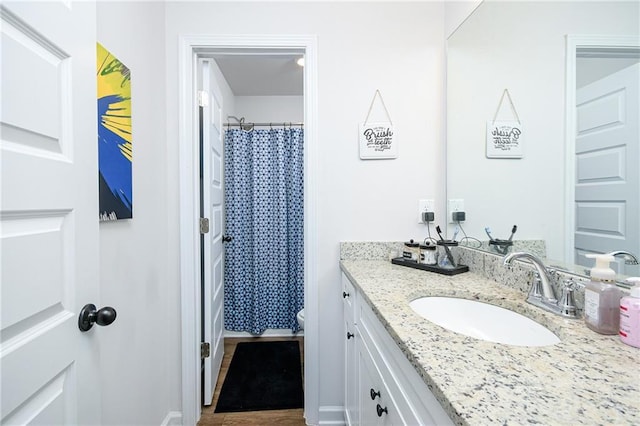 bathroom with a shower with shower curtain, vanity, hardwood / wood-style flooring, and toilet