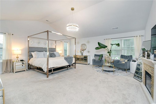 carpeted bedroom featuring vaulted ceiling, multiple windows, a notable chandelier, and a stone fireplace