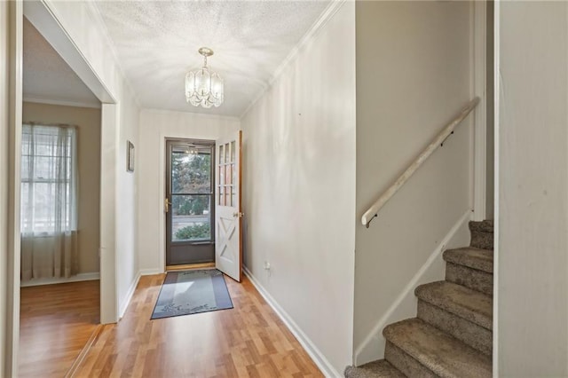 entrance foyer with light wood-type flooring, crown molding, and an inviting chandelier