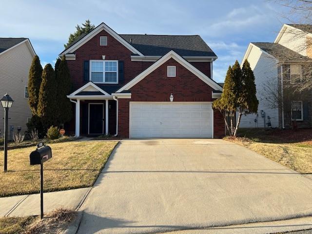 traditional home with a garage, concrete driveway, brick siding, and a front lawn