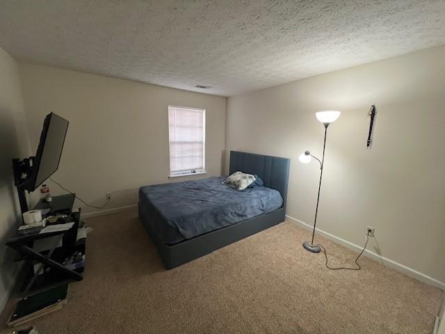 bedroom featuring visible vents, baseboards, dark colored carpet, and a textured ceiling