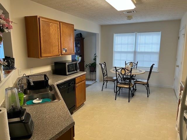 kitchen with stainless steel microwave, visible vents, brown cabinetry, a sink, and dishwasher