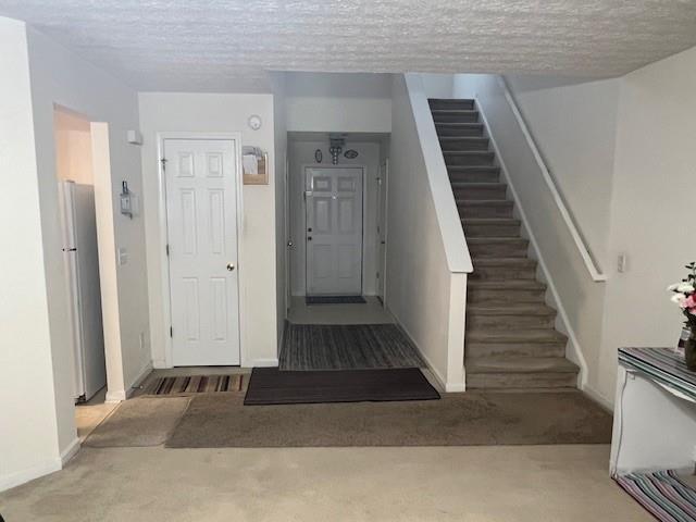 stairs with baseboards, a textured ceiling, and carpet flooring