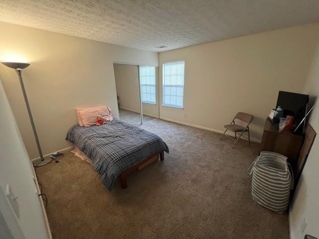 carpeted bedroom with a textured ceiling and baseboards