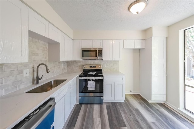 kitchen featuring sink, backsplash, stainless steel appliances, and white cabinets