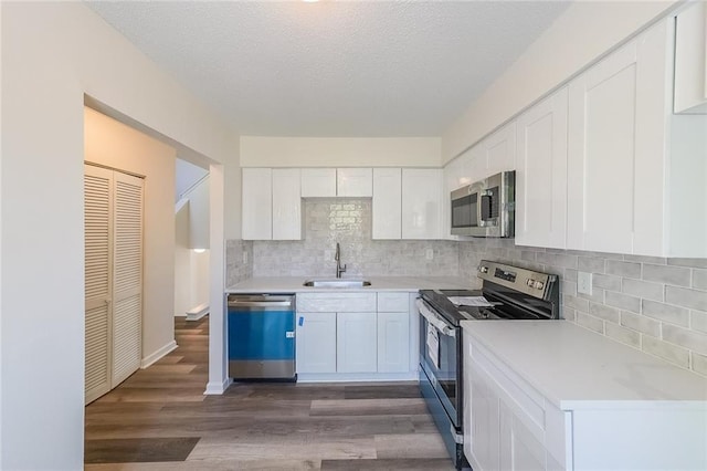 kitchen featuring appliances with stainless steel finishes, white cabinetry, sink, backsplash, and dark hardwood / wood-style flooring