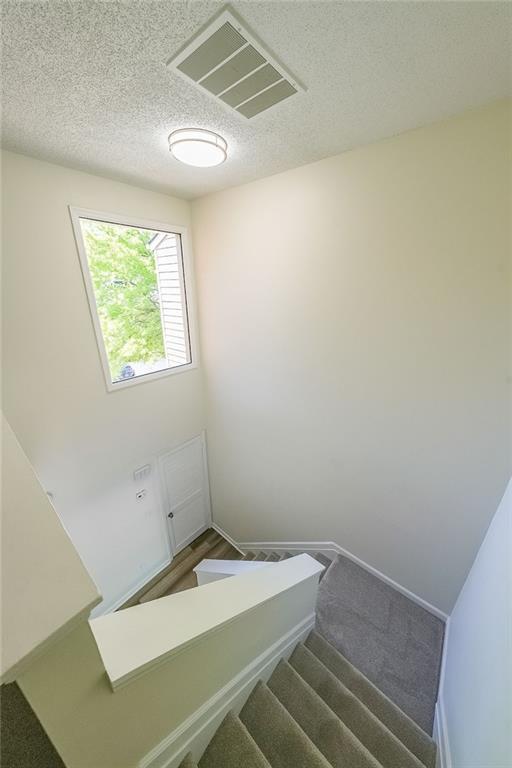 stairway featuring a textured ceiling