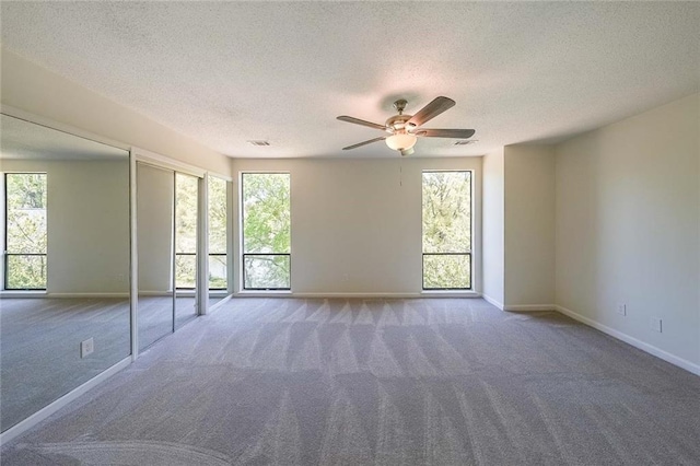 empty room with ceiling fan, a textured ceiling, and carpet flooring