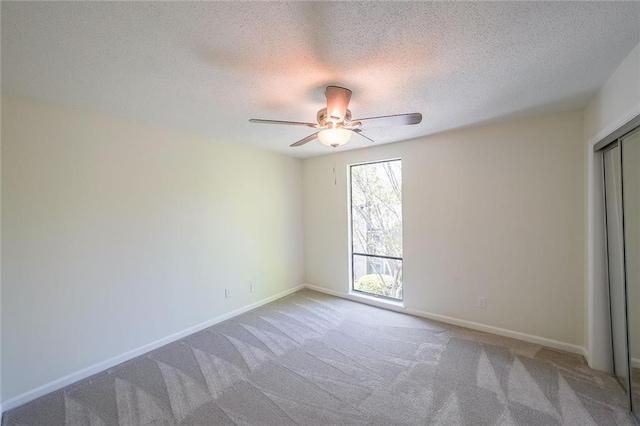 carpeted empty room with ceiling fan and a textured ceiling