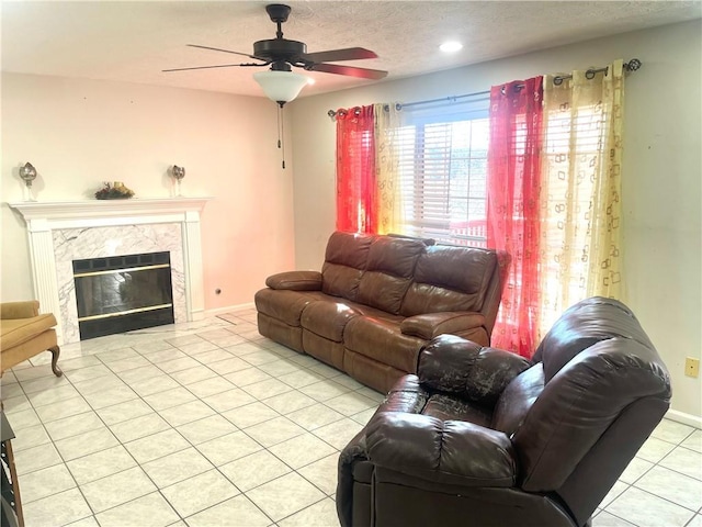 living room featuring a fireplace, a textured ceiling, baseboards, and light tile patterned floors