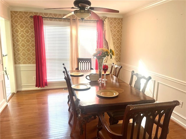 dining room with ornamental molding, wainscoting, hardwood / wood-style floors, and wallpapered walls