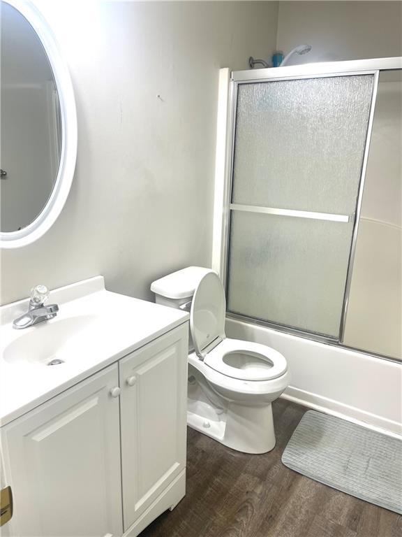 full bathroom with shower / bath combination with glass door, vanity, toilet, and wood finished floors