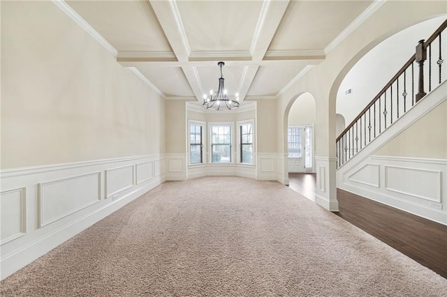 interior space with a chandelier, carpet flooring, ornamental molding, and beamed ceiling