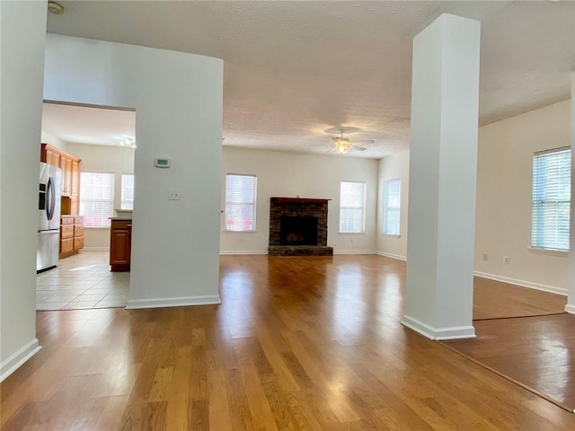 unfurnished living room featuring ceiling fan, light wood-type flooring, and a wealth of natural light