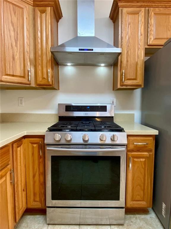 kitchen with gas stove, wall chimney exhaust hood, and black fridge