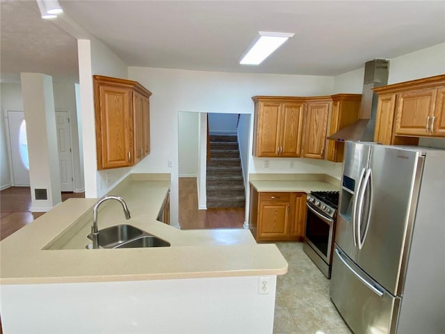 kitchen with wall chimney range hood, sink, and appliances with stainless steel finishes