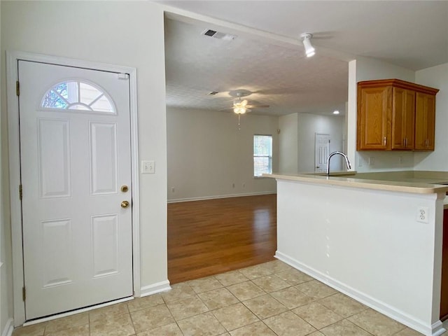 kitchen featuring sink, kitchen peninsula, ceiling fan, and light tile patterned flooring