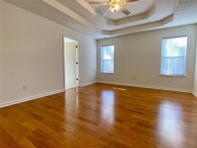 spare room featuring hardwood / wood-style flooring, ceiling fan, and a raised ceiling