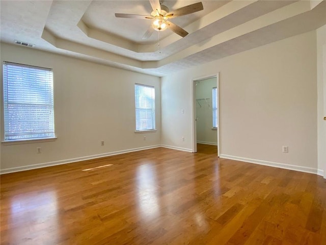 spare room with hardwood / wood-style flooring, a raised ceiling, and ceiling fan