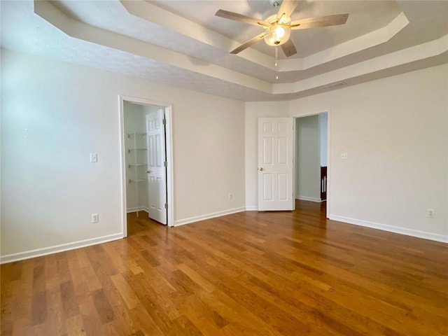 spare room featuring hardwood / wood-style flooring, ceiling fan, and a tray ceiling