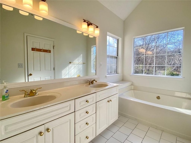 bathroom featuring tile patterned flooring, a washtub, vaulted ceiling, and a wealth of natural light