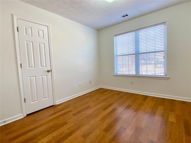 spare room featuring hardwood / wood-style flooring and a textured ceiling