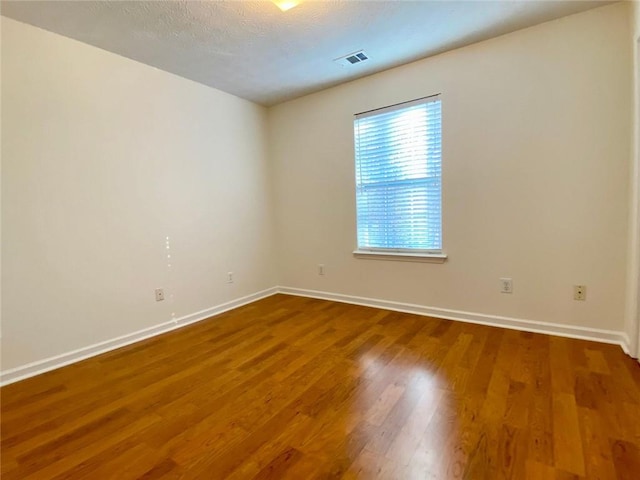 empty room featuring hardwood / wood-style flooring and a textured ceiling