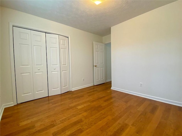 unfurnished bedroom with hardwood / wood-style floors, a closet, and a textured ceiling