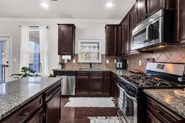 kitchen featuring crown molding, sink, light stone countertops, dark brown cabinetry, and stainless steel appliances