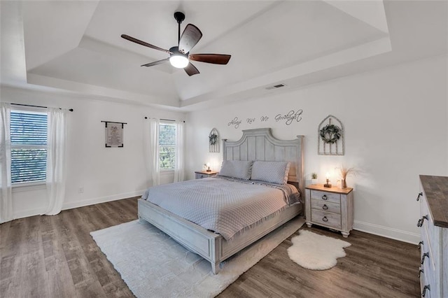 bedroom featuring a tray ceiling, ceiling fan, and dark hardwood / wood-style flooring