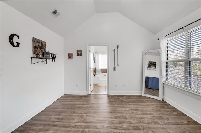 interior space with dark wood-type flooring, a wealth of natural light, and lofted ceiling